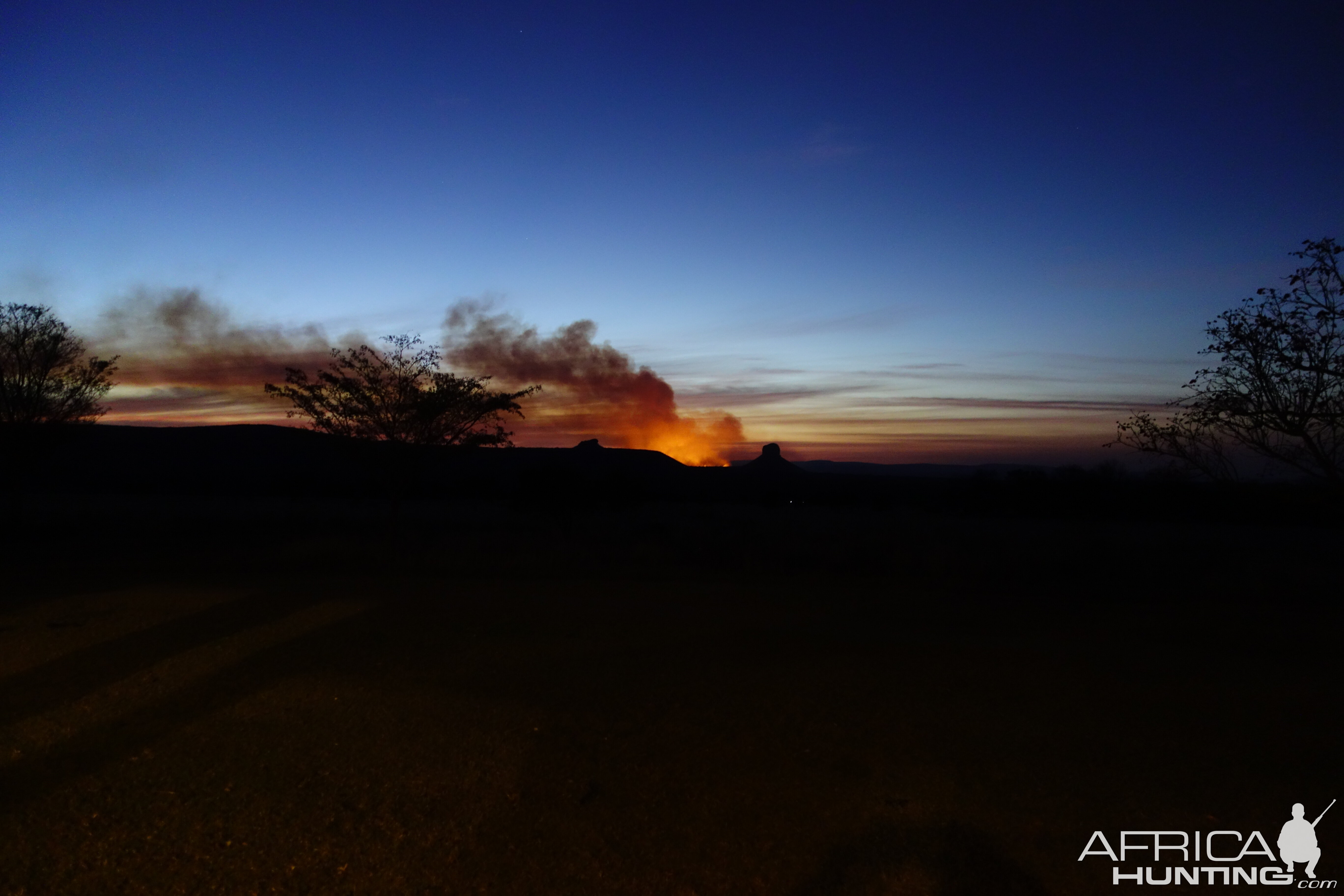 In the distance, a bush fire burns